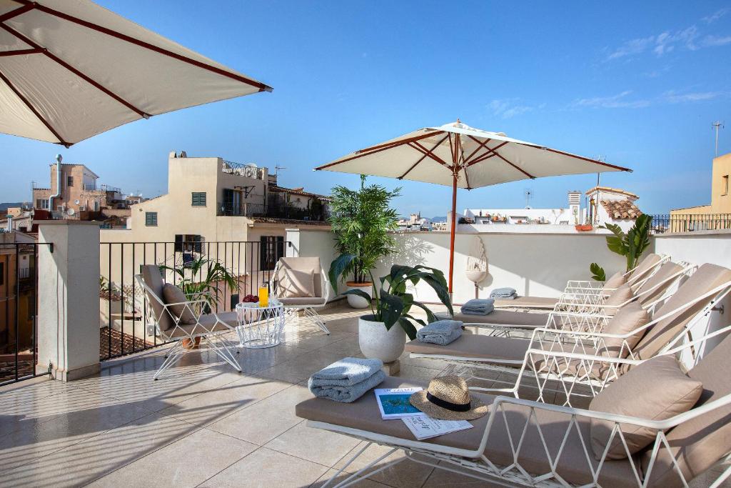 eine Terrasse mit Stühlen und Sonnenschirmen auf dem Dach in der Unterkunft Samaritana Suites in Palma de Mallorca