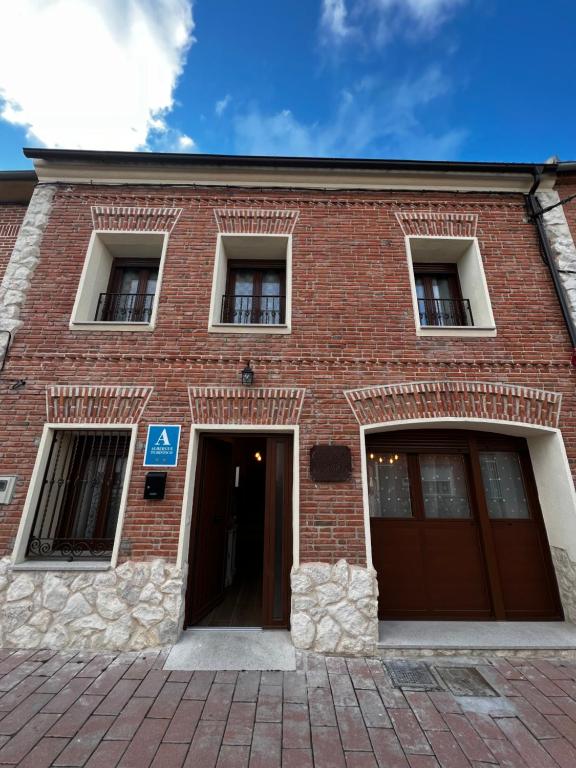 ein rotes Backsteingebäude mit zwei Eingängen und zwei Fenstern in der Unterkunft Casa Aurora in Sanchidrián