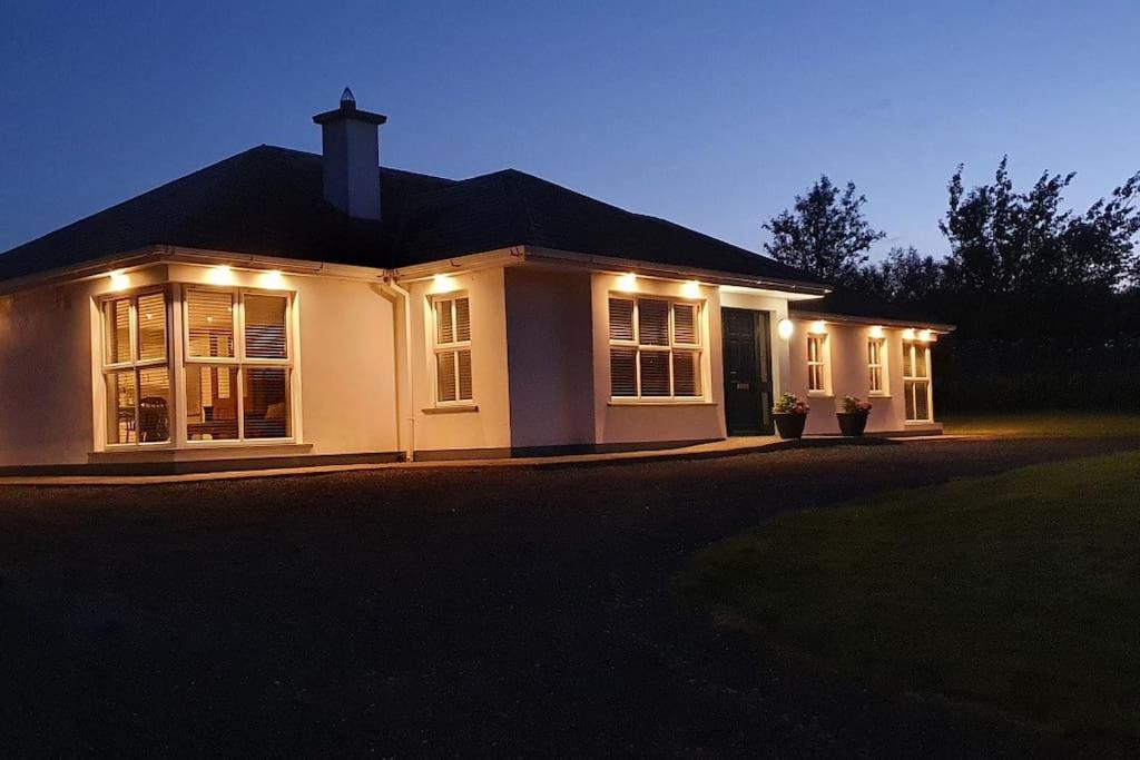 Una casa blanca con luces en la parte delantera. en Superb 4 Bed / 3 Bath Bungalow in Mitchelstown, en Mitchelstown