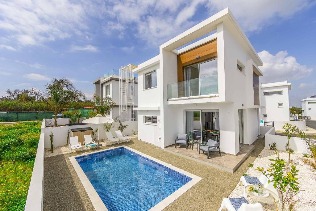 a white house with a swimming pool in front of it at Villa Alasia in Paralimni