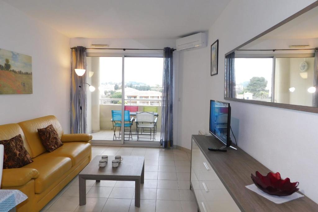 uma sala de estar com um sofá e uma televisão em Charming T2 "Antibes Les Pins 3" air-conditioned with parking and swimming em Antibes