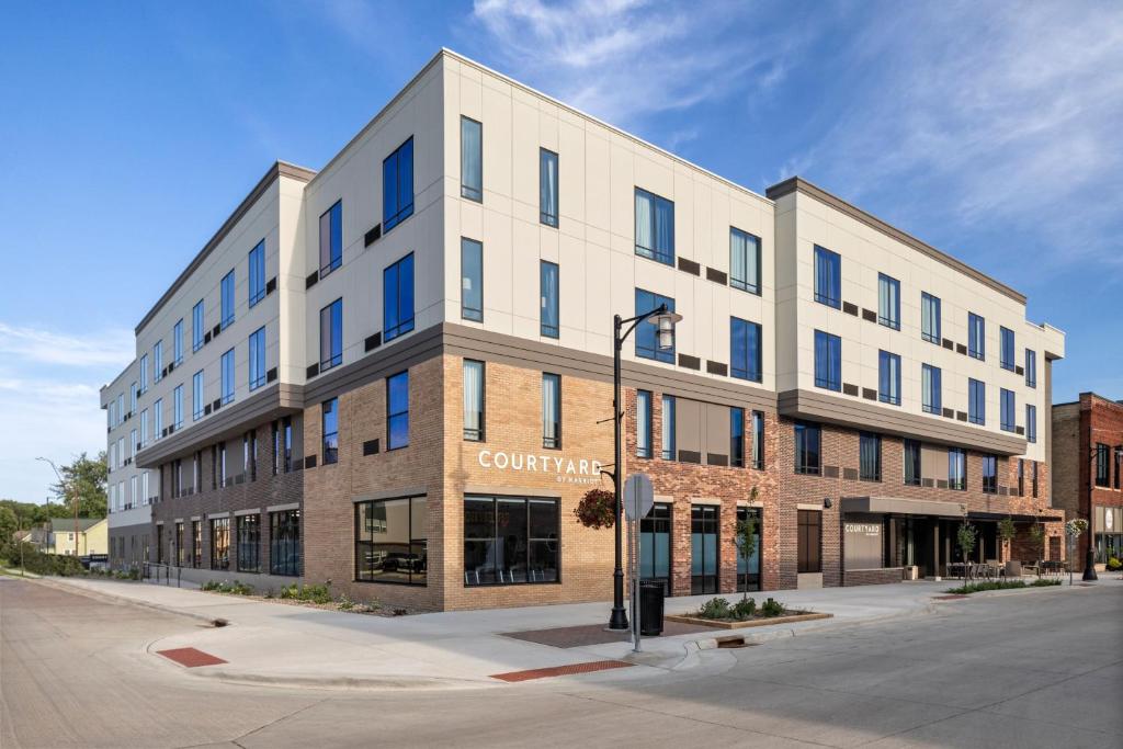 um grande edifício branco numa rua com uma luz de rua em Courtyard by Marriott Owatonna Downtown em Owatonna