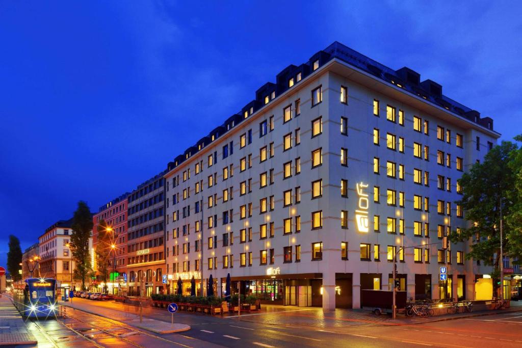 a large white building on a city street at night at Aloft München in Munich