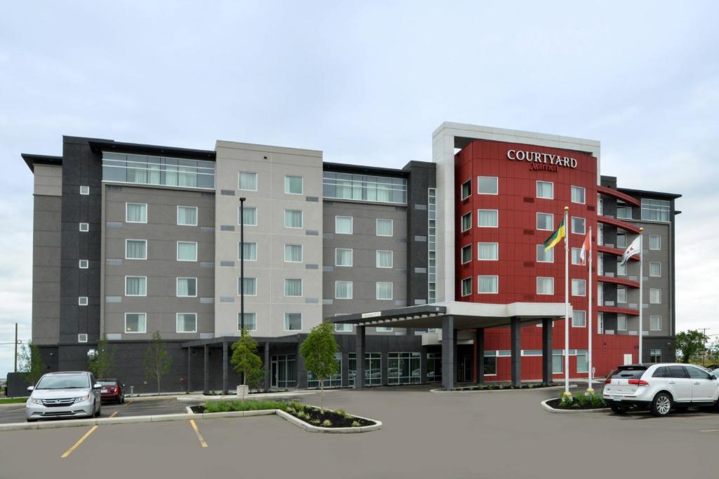 a building with cars parked in a parking lot at Courtyard by Marriott Saskatoon Airport in Saskatoon