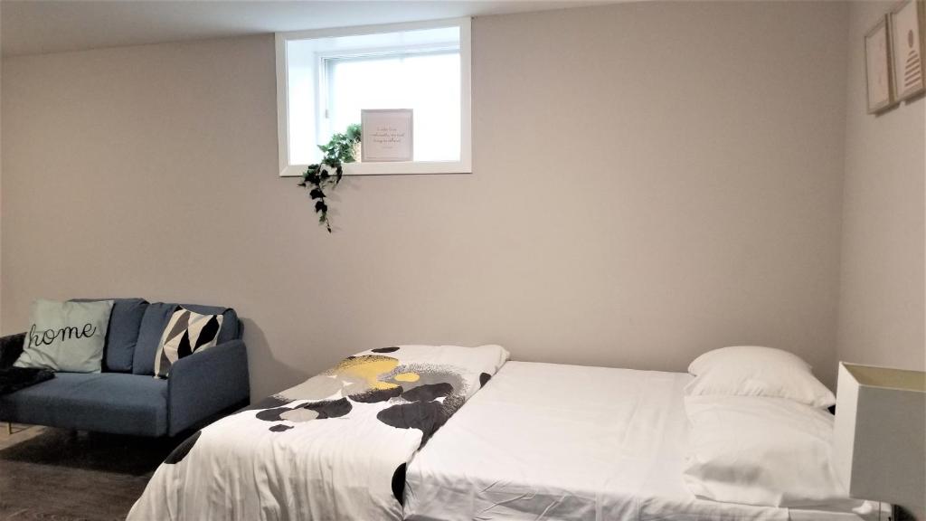 a bedroom with a bed and a chair and a window at Charming Studio with Parking, Netflix, Full Kitchen - Close to Algonquin College in Ottawa