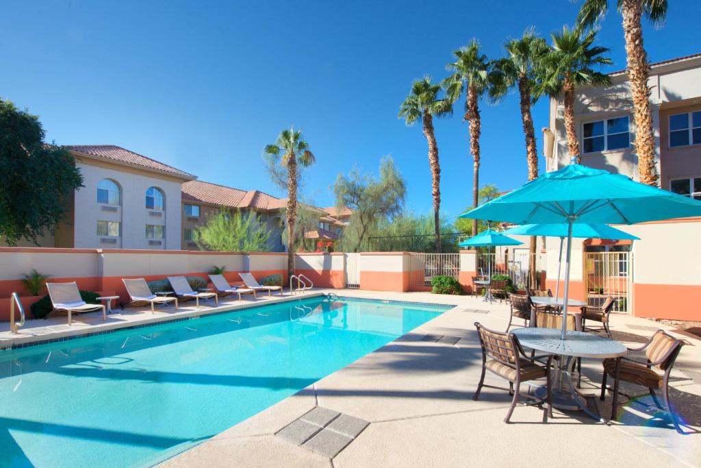 basen z krzesłami i stół z parasolem w obiekcie Residence Inn Phoenix Mesa w mieście Mesa