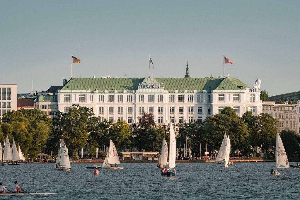 a group of sailboats in the water in front of a building at Hotel Atlantic Hamburg, Autograph Collection in Hamburg