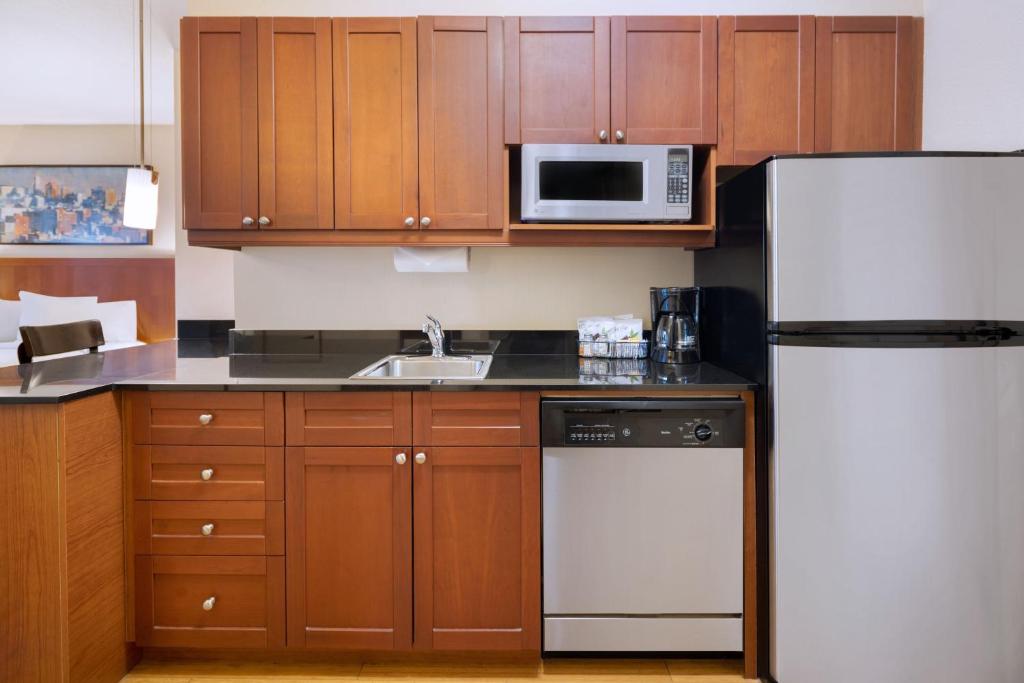 a kitchen with wooden cabinets and a white refrigerator at Residence Inn by Marriott New York Manhattan/Times Square in New York