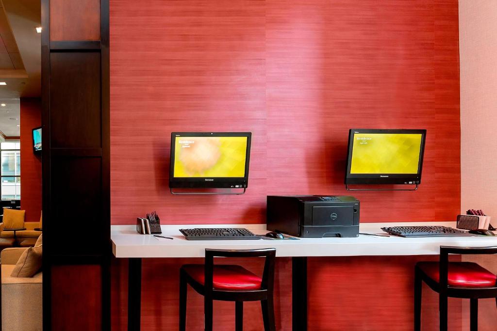 a desk with two computer monitors on a red wall at Residence Inn by Marriott New York Manhattan/Times Square in New York