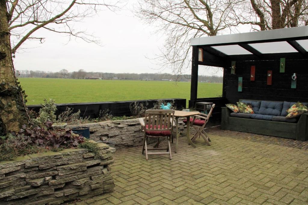 een patio met een tafel en stoelen en een bank bij 't Prentenhokkie in Stuifzand