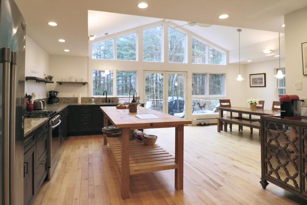 uma cozinha com uma mesa de madeira e uma grande janela em Woodland Hills Modern Cottage Minutes from Downtown Great Barrington em Great Barrington