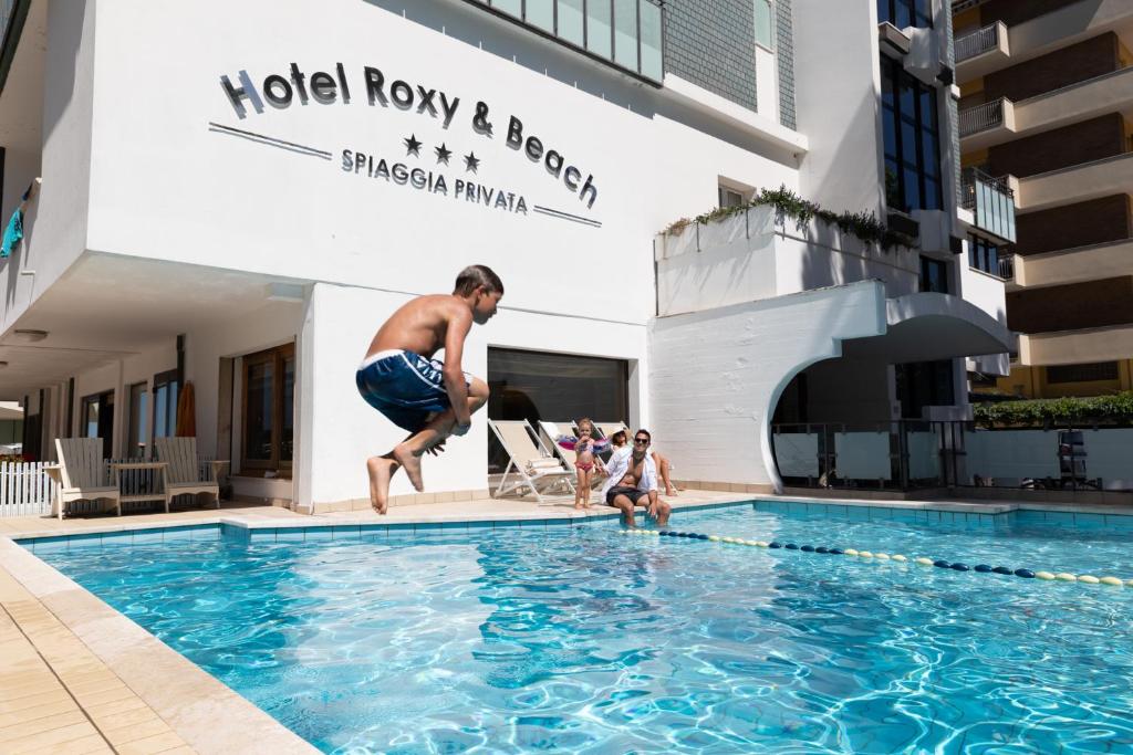 a man jumping into a swimming pool at a hotel at Hotel Roxy & Beach in Cesenatico