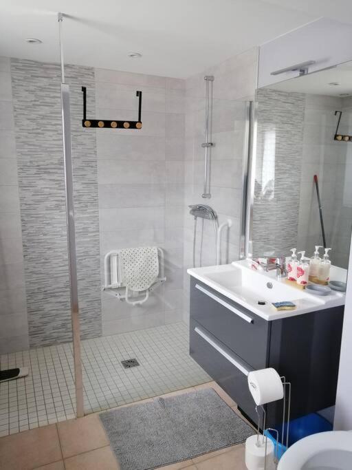 une salle de bain blanche avec un lavabo et une douche dans l'établissement Charmante petite maison de vacances, à Saint-Clair-de-Halouze