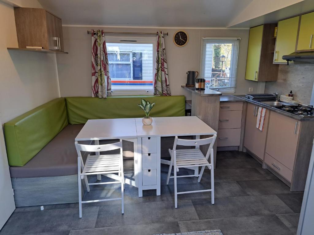 eine kleine Küche mit einem Tisch, Stühlen und einem Sofa in der Unterkunft Mobil home confort 6 personnes in Saint-Chéron