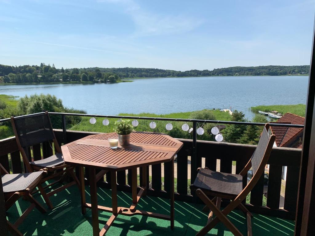 a table and chairs on a balcony with a view of a lake at Apartment am See in Scharbeutz