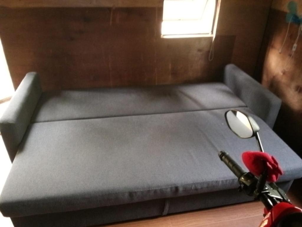 una cama azul con un animal de peluche rojo sentado al lado en Small cosy house (simple but complete), en Asgad