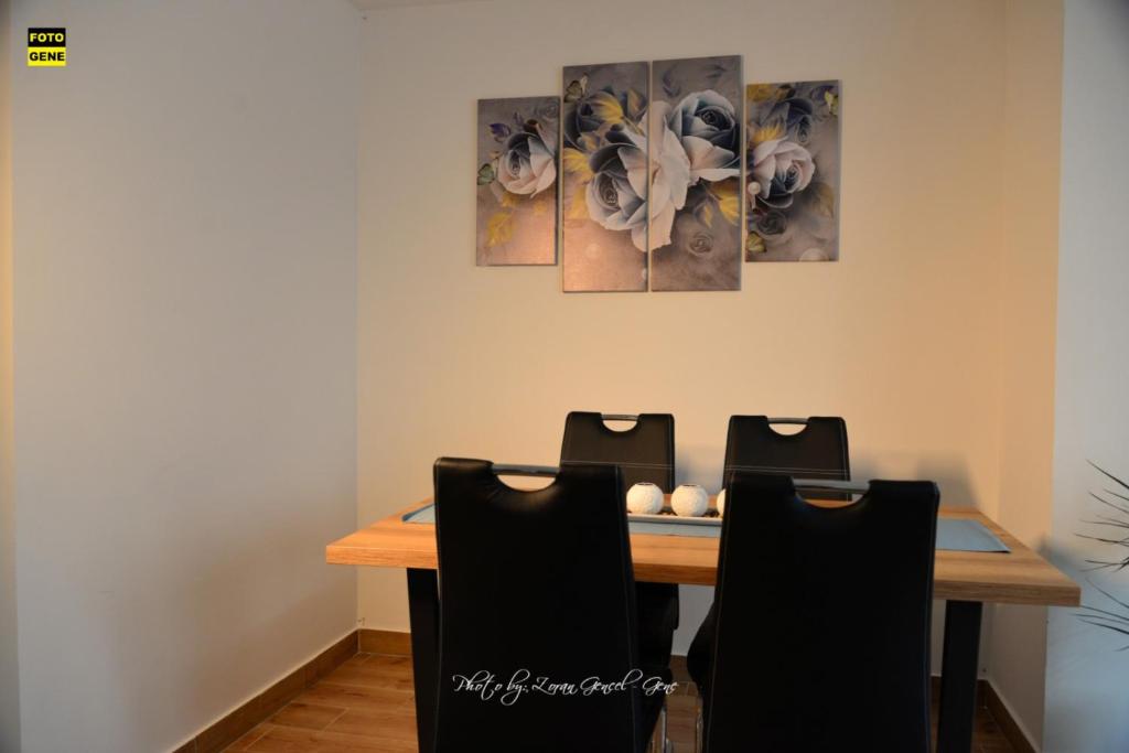 a dining room table with chairs and paintings on the wall at Apartment No 11 in Subotica