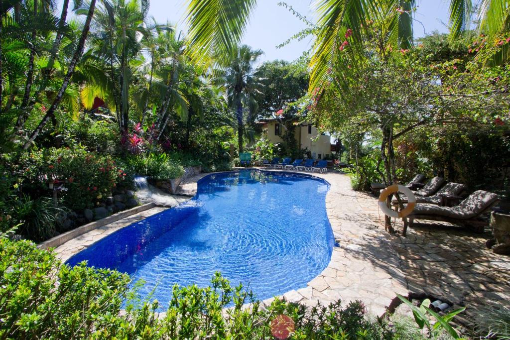einen Pool in einem Garten mit Palmen in der Unterkunft Hotel Villas Nicolas - Adults Only in Manuel Antonio