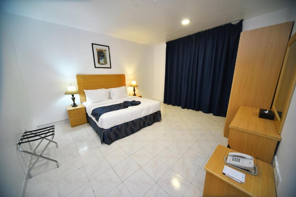 a hotel room with a bed and a desk at Alain Hotel Apartments Ajman in Ajman 