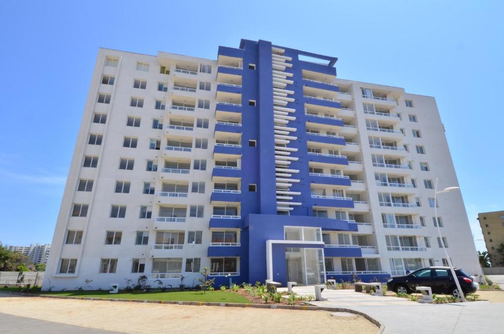 Il propose un grand appartement blanc doté d'une façade bleue. dans l'établissement Departamento con vista al Mar, à La Serena