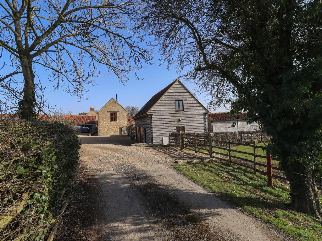 a dirt road with two houses and a barn at Granary Loft in Grantham