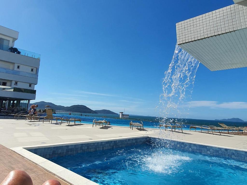 una piscina con una fuente frente al océano en Apto de Luxo Mirante Home Club, Magnífico Mar dos Ingleses, en Florianópolis