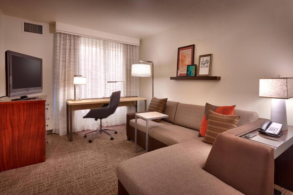 a living room with a couch and a desk in a hotel room at Residence Inn Salt Lake City Sandy in Sandy