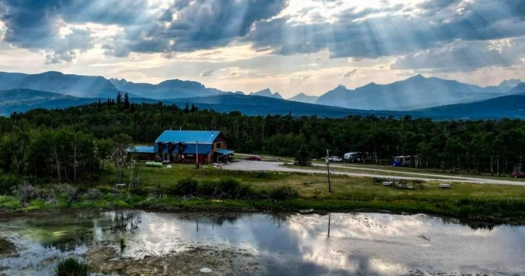 a building with a blue roof next to a river at Duck Lake Lodge in Babb