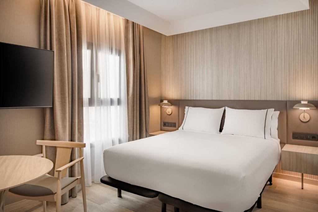 a bedroom with a large white bed and a table at AC Hotel by Marriott Tenerife in Santa Cruz de Tenerife