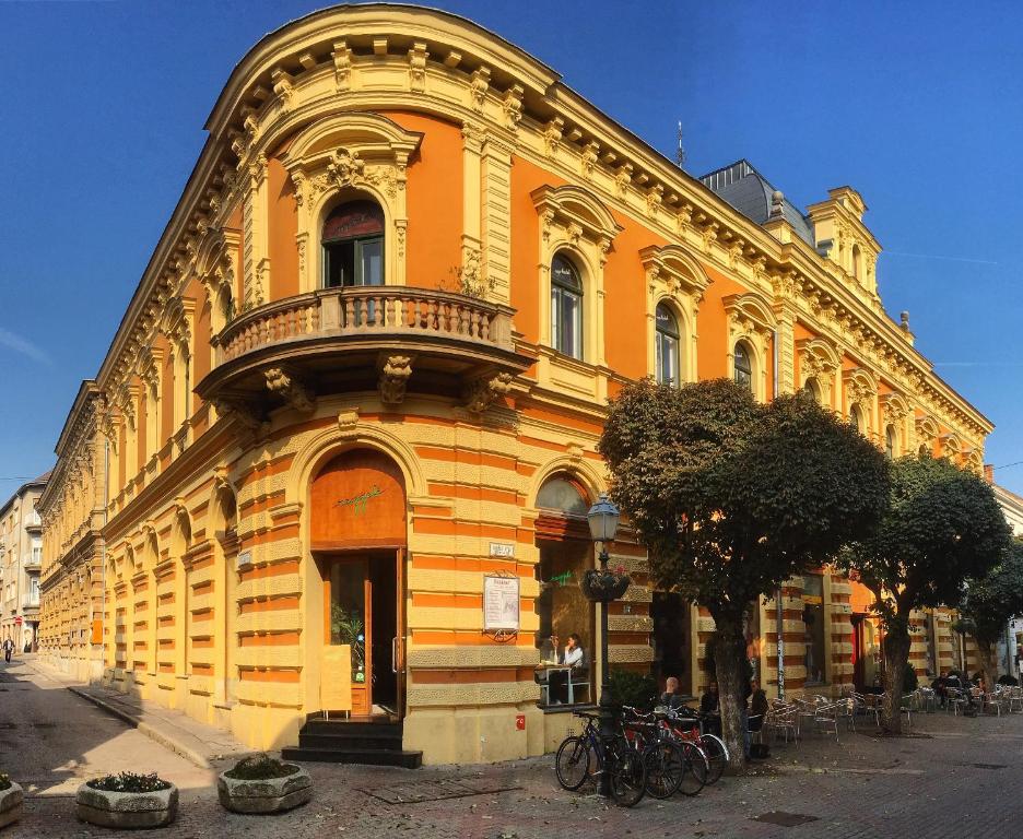 un gran edificio amarillo con balcón en una calle en NAPartman Pécs, en Pécs