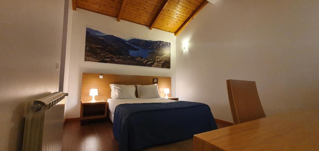 sypialnia z łóżkiem i obrazem na ścianie w obiekcie Bungalows - Serra do Gerês w mieście Campo do Gerês