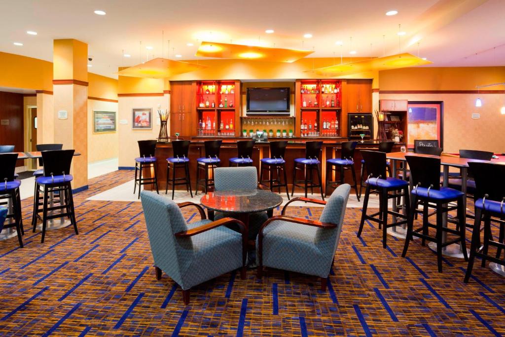 a lobby with a bar with chairs and tables at Courtyard Minneapolis Maple Grove Arbor Lakes in Maple Grove