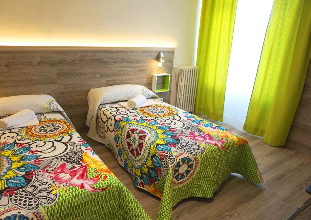 2 camas en una habitación con cortinas verdes en MuchoMadrid en Madrid