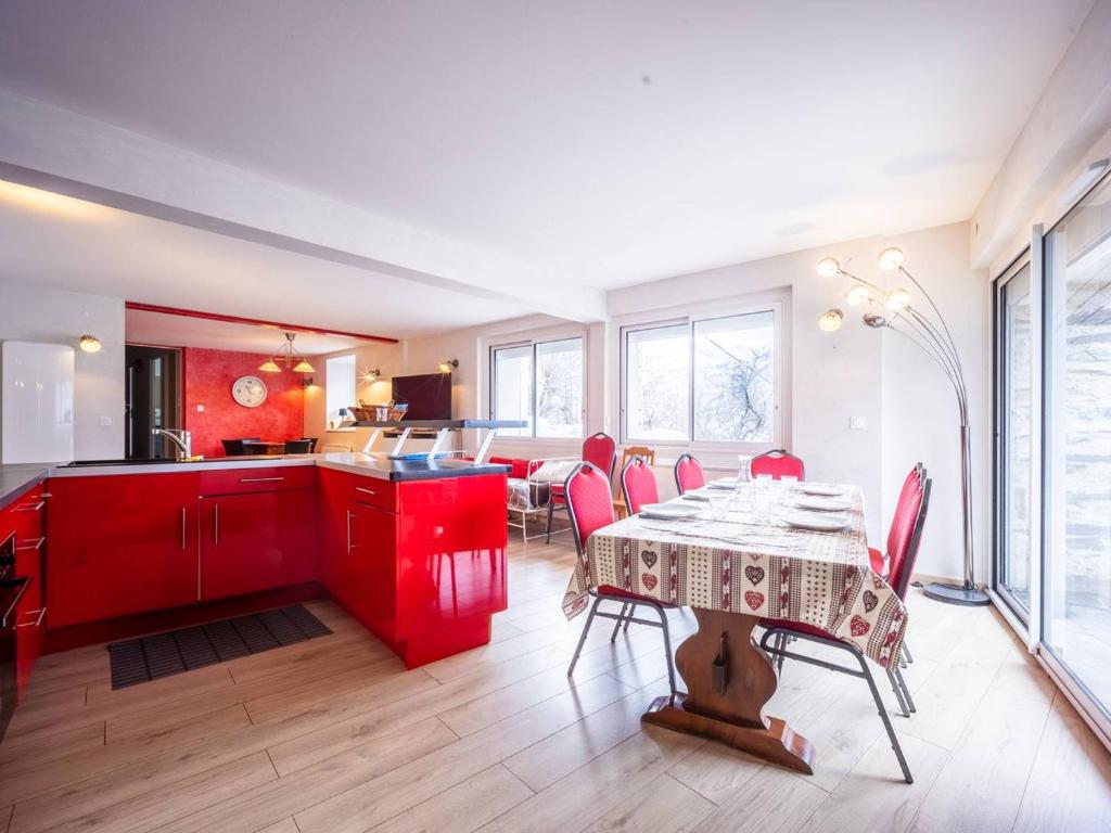 uma cozinha com armários vermelhos e uma mesa com cadeiras em Maison Estarvielle, 5 pièces, 10 personnes - FR-1-695-25 