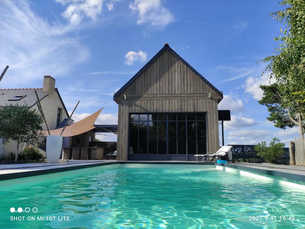 une maison avec une piscine en face d'un bâtiment dans l'établissement La Cabane Bois des Roses, à Les Rosiers