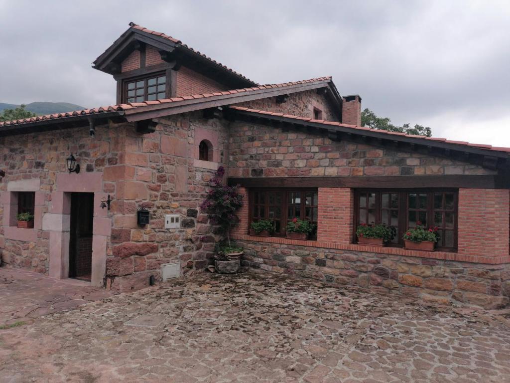 un antiguo edificio de ladrillo con plantas en las ventanas en Casa de campo El Midiaju para 8 personas, en Carmona