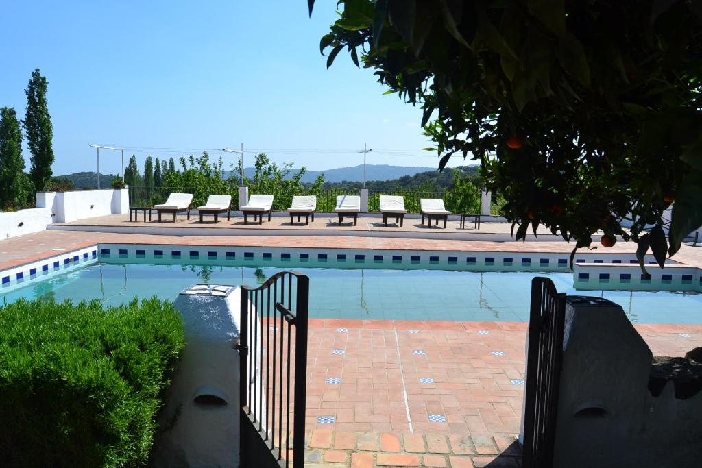 a swimming pool with chairs and a fence next to it at Las Navezuelas in Cazalla de la Sierra