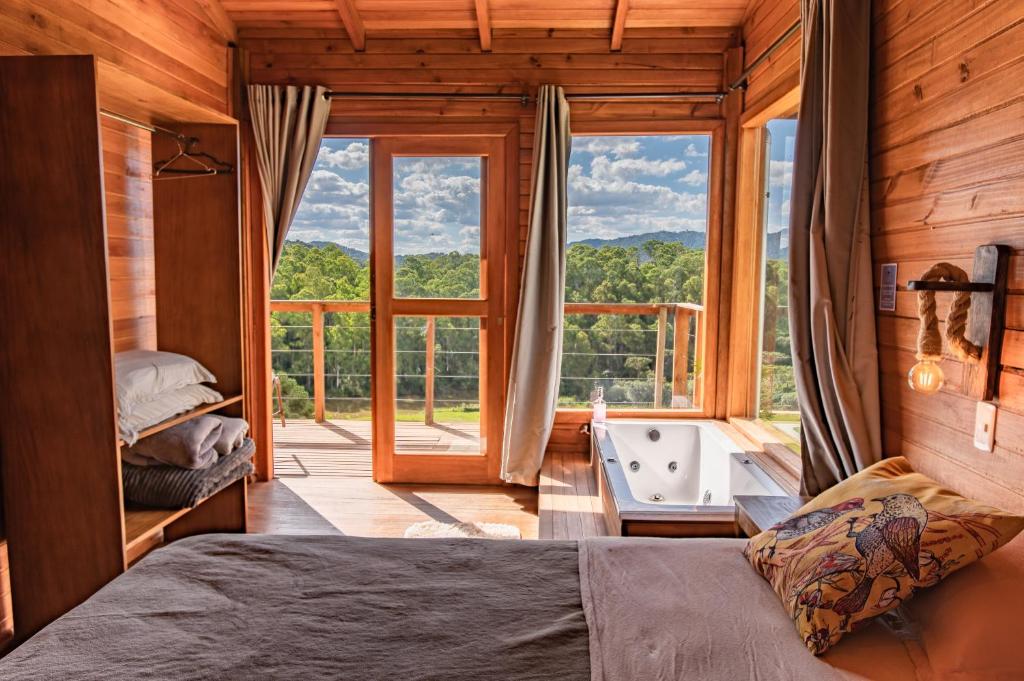 1 dormitorio con cama, bañera y ventana en Refúgio do Sol Campestre, en Urubici