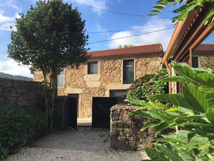 a stone house with a gate and a tree at Lugar do Curro, San Martiño de Ozón in Muxia