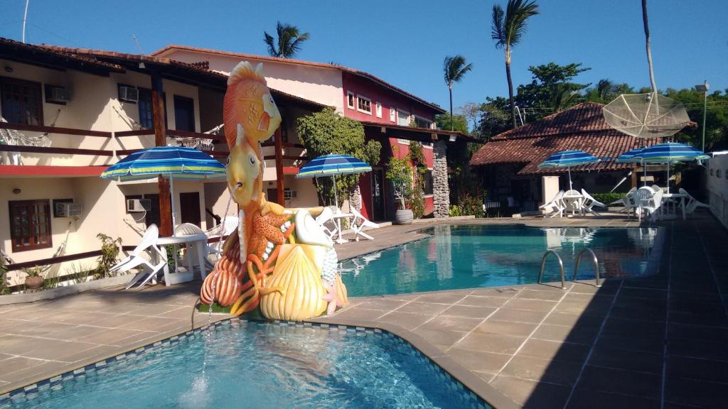a resort swimming pool with a statue of a fish at Taperapuan Praia Hotel in Porto Seguro