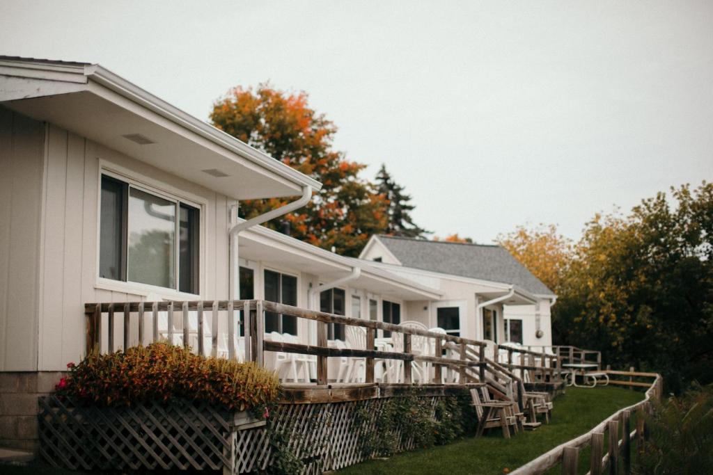 een wit huis met een houten terras in de tuin bij Seagull Bay Motel in Bayfield