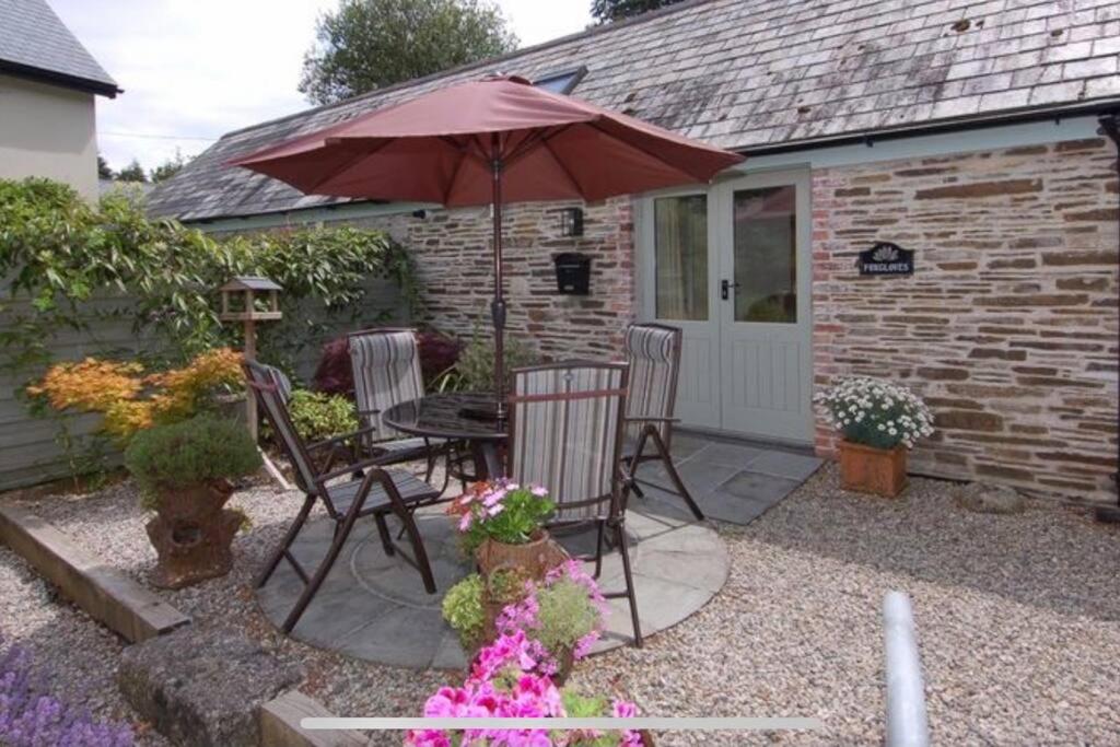a patio with a table and an umbrella at Maristow Cottages, overlook Tamar Valley Dartmoor in Plymouth