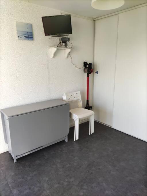 Pokój z telewizorem, stołem i krzesłem w obiekcie Superbe studio dans résidence avec piscine sans chambre mais couchage salle et lit superposé dans l'entrée w mieście Le Grau-du-Roi
