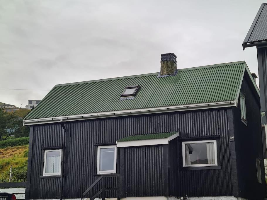 una casa negra con techo verde en Hyggeligt gammelt hus i Vestmanna, en Vestmanna