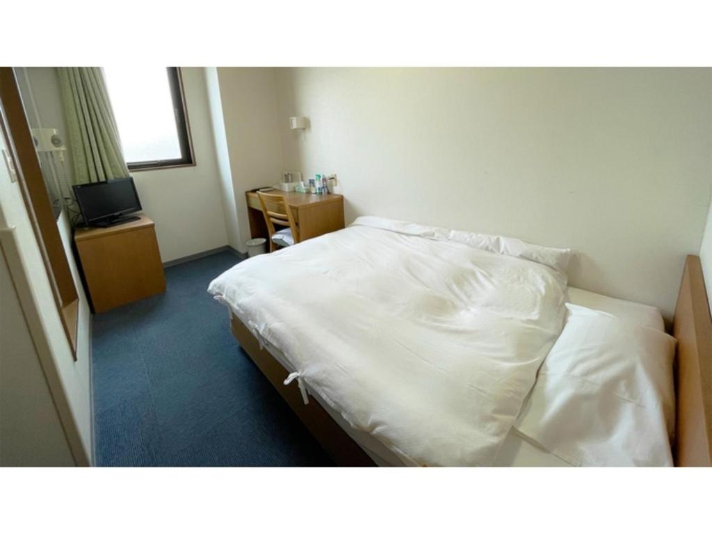 una camera da letto con un letto con lenzuola bianche e una TV di Business Hotel Lupinus - Vacation STAY 55803v a Takamatsu