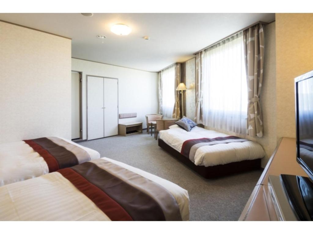 Cette chambre comprend deux lits et une télévision. dans l'établissement Hotel Areaone Hiroshima Wing - Vacation STAY 62261v, à Higashihiroshima