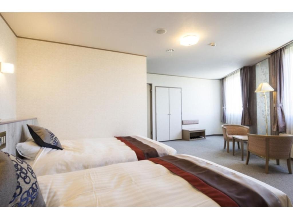 Habitación de hotel con 2 camas y mesa en Hotel Areaone Hiroshima Wing - Vacation STAY 62250v, en Higashihiroshima