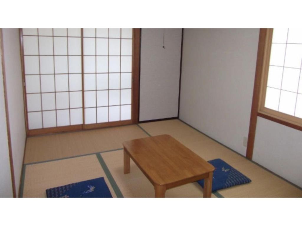 um quarto com uma mesa de madeira e dois tapetes azuis em Pals Inn Raicho - Vacation STAY 74722v em Iida