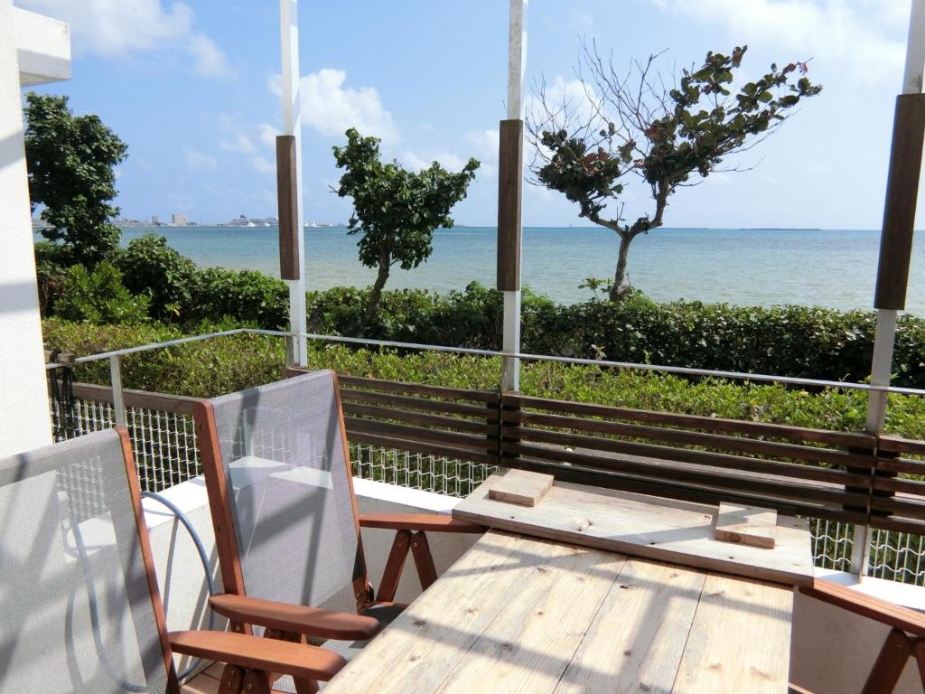 um alpendre com uma mesa e cadeiras e o oceano em Seacore Villa - Vacation STAY 14248 em Ishigaki