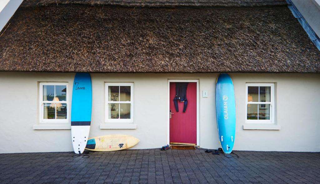 un grupo de tablas de surf apoyadas en una casa en Red Cliff Lodge, en Spanish Point